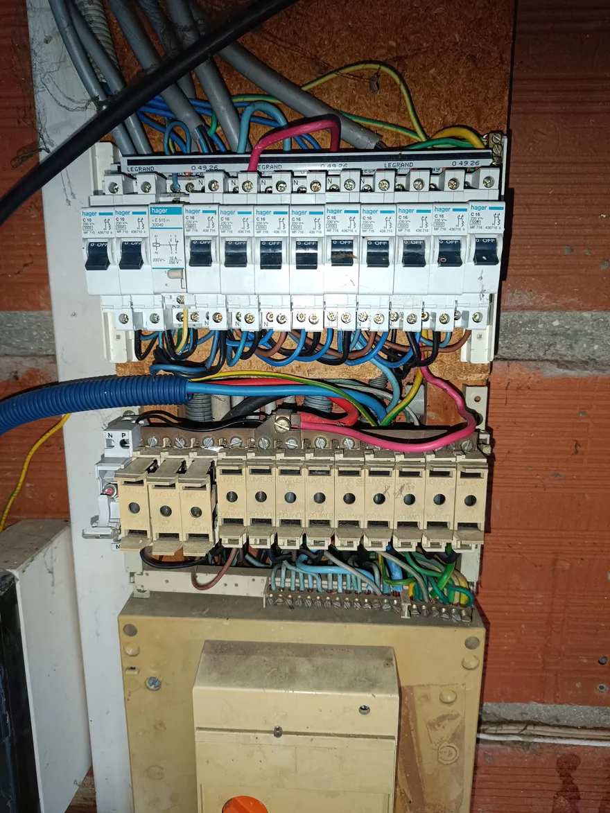 Tableau électrique ouvert en cours de câblage, rangées de disjoncteurs et fils repérés